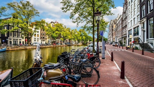 A row of bikes lined up by a canal in Amsterdam on a sunny day